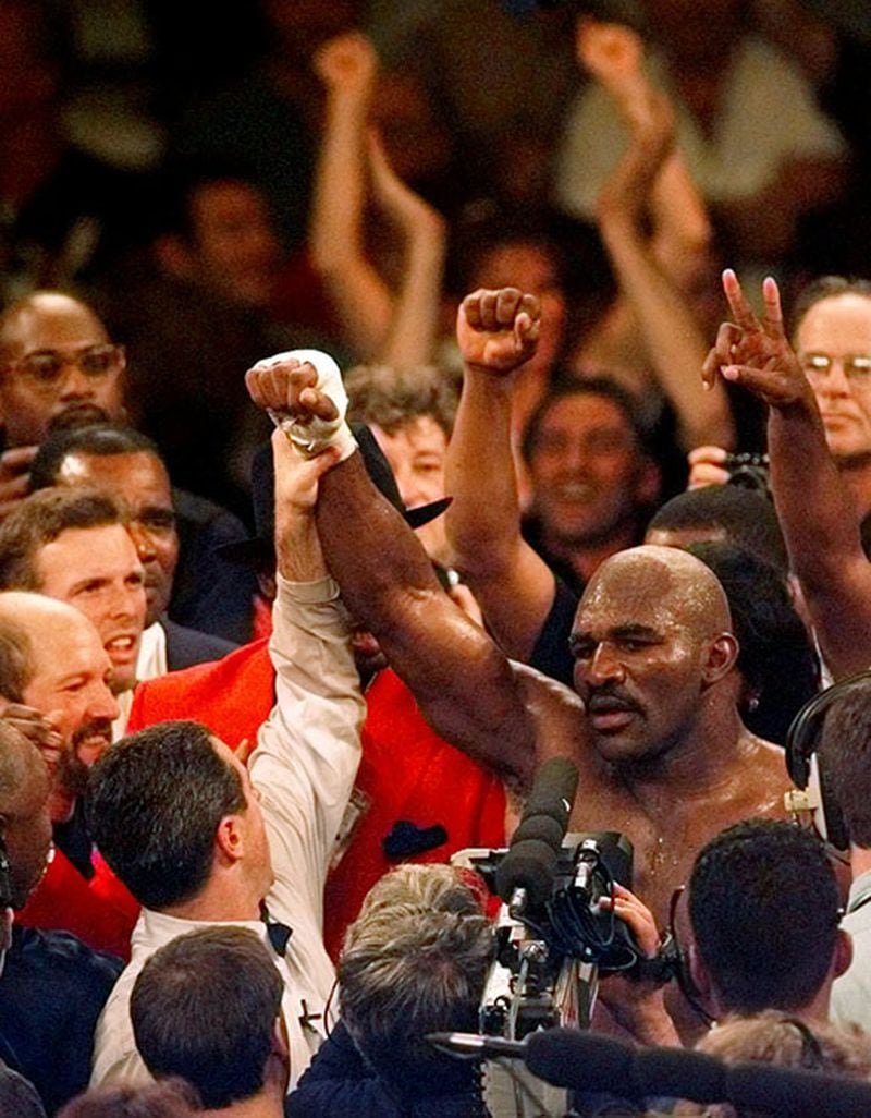 Evander Holyfield's arm is raised in victory after his TKO of Mike Tyson.