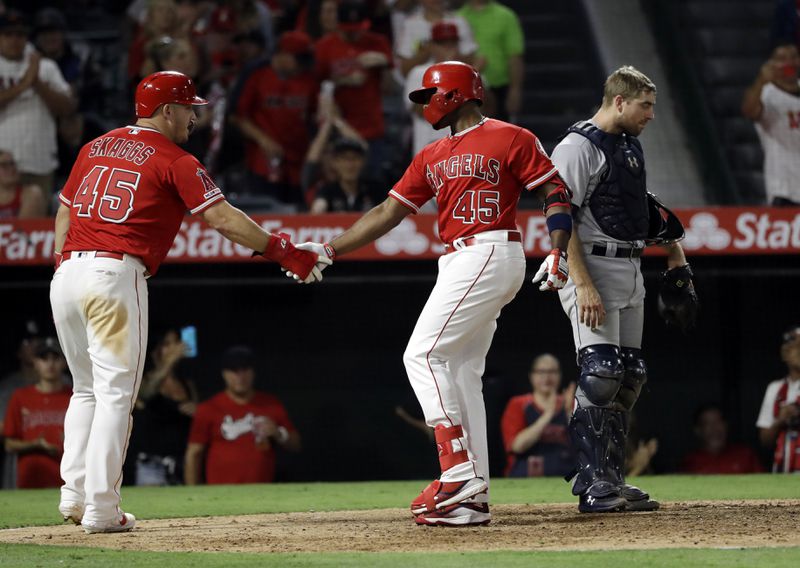 Los Angeles Angels' Justin Upton, center, is met at home plate by teammate Mike Trout, left, after Upton's two-run home run against the Seattle Mariners during the seventh inning of a baseball game Friday, July 12, 2019, in Anaheim, Calif. (AP Photo/Marcio Jose Sanchez)