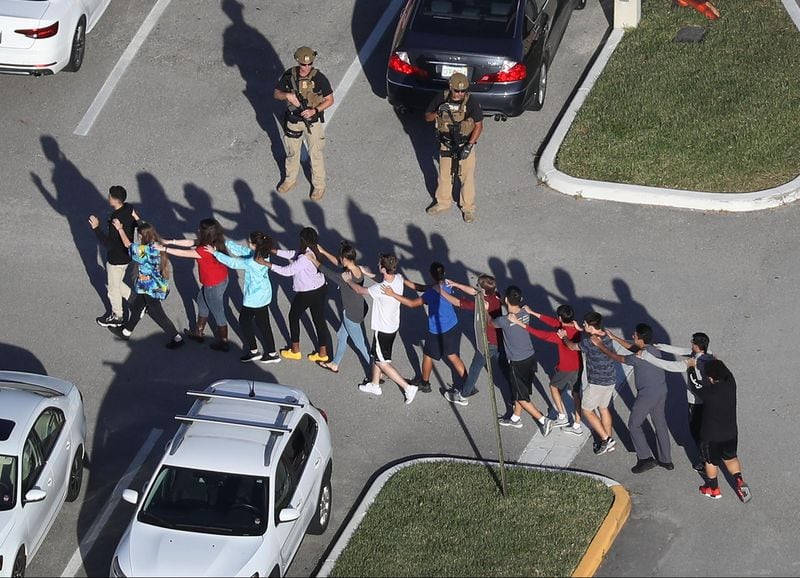 People are brought out of the Marjory Stoneman Douglas High School after a shooting at the school that killed 17 people in Parkland, Florida.