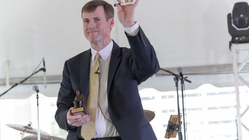 Cox Washington bureau radio reporter Jamie Dupree waves to the audience at a Town Hall meeting of Cox Enterprises employees. Dupree holds in his right hand the Governor Cox Award, which he was presented at the meeting. CONTRIBUTED