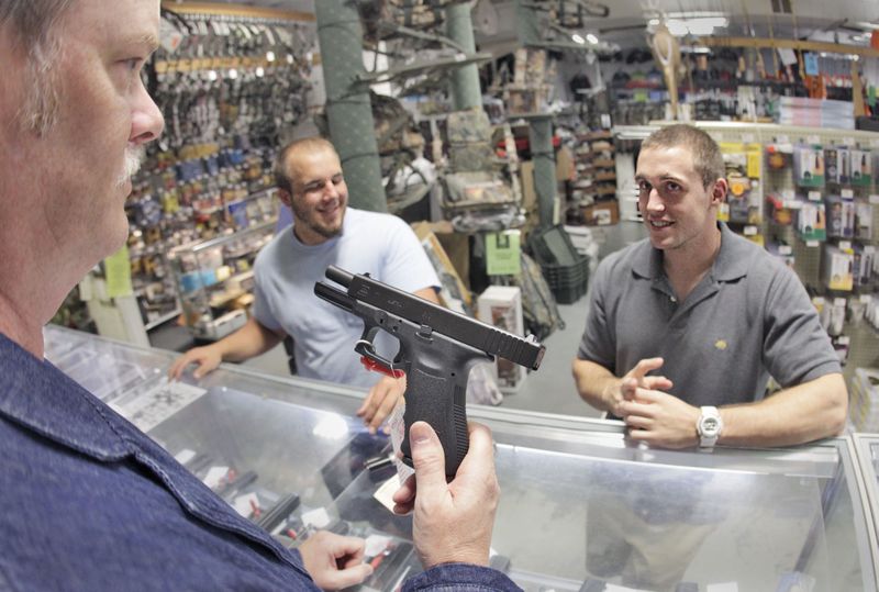 Rob Abrams, left, shows customers a Glock 17 at Adventure Outdoors in Smyrna, where Glock Inc. is headquartered, in this 2010 photo. Massachusetts' attorney general launched a consumer protection investigation into the company last year, even though Glock can't sell directly to consumers there because its guns don't meet state safety requirements. BOB ANDRES BANDRES@AJC.COM
