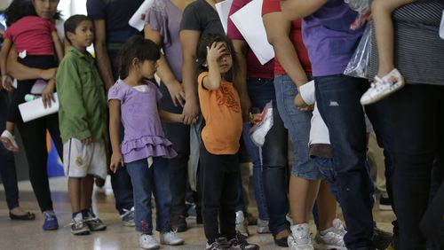 In this June 20, 2014 photo, immigrants who entered the U.S. illegally stand in line for tickets at the bus station after they were released from a U.S. Customs and Border Protection processing facility in McAllen, Texas. The immigrants entered the country through an area referred to as zone nine. (AP Photo/Eric Gay)