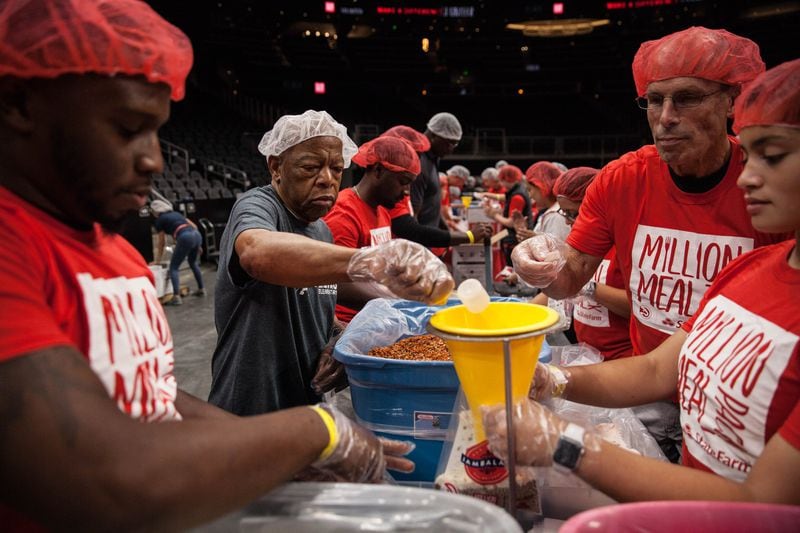 U.S. Rep. John Lewis (center left) helps pack food with volunteers during the event to package 1 million meals at State Farm Arena, Saturday, Oct. 5, 2019, in Atlanta. BRANDEN CAMP/SPECIAL TO THE AJC