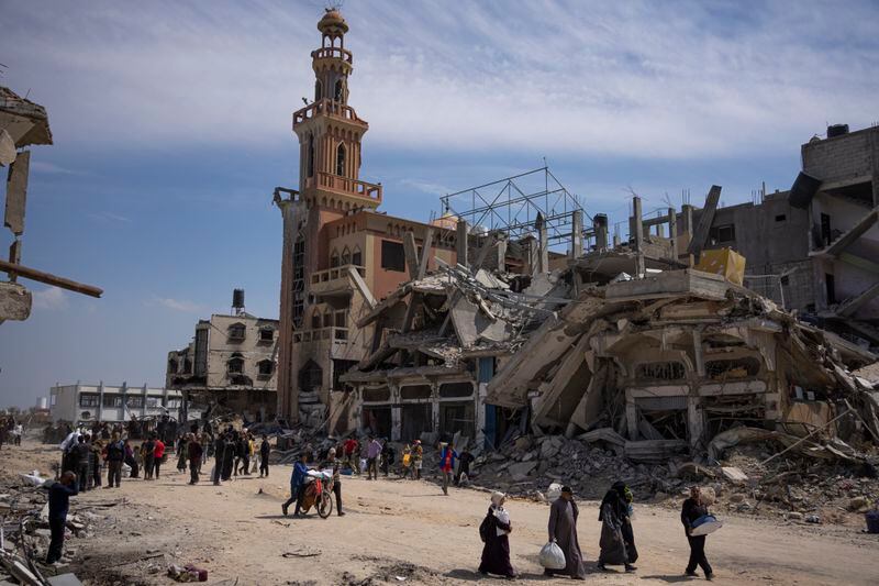 Palestinians walk through the destruction in the wake of an Israeli air and ground offensive in Khan Younis, southern Gaza Strip, Monday, April 8, 2024. Israel says it has withdrawn its last ground troops from the city, ending a four-month operation. (AP Photo/Fatima Shbair)