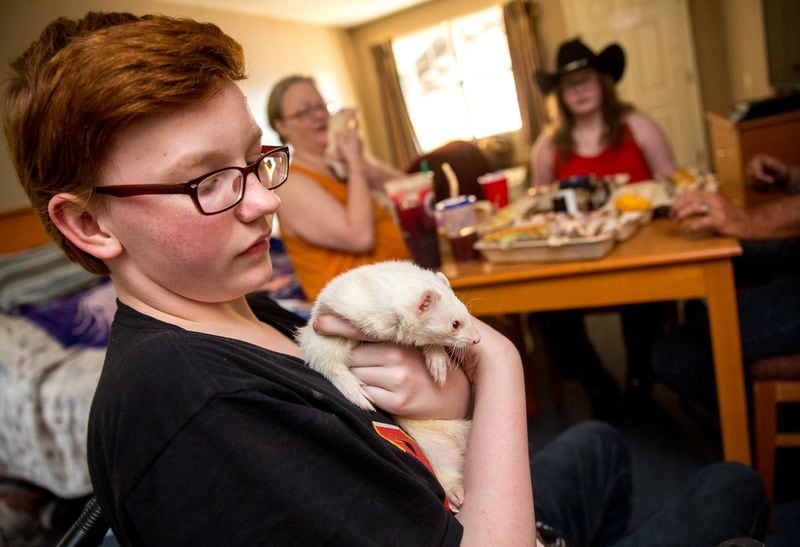 The Perdue family has dinner while 15-year-old Zachary puts away one of their two ferrets Friday, June 25, 2021 in their room at the Whits Inn, an extended stay hotel in Loganville where they live. (Jenni Girtman for The Atlanta Journal-Constitution)
