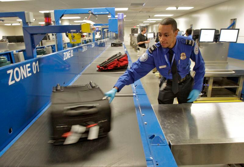 May 2, 2012 - Hartsfield Jackson International Airport - Blake Rushmore, Lead Officer in the baggage inspection room, pulls a bag that has been flagged for a physical check by the Explosive Detection System. As a "dress rehearsal" for it's opening later this month, Hartsfield recruited 1600 volunteers for a simulation exercise. The volunteers were given a script with boarding passes and told to bring their luggage as part of a massive exercise to test potential bottlenecks at the airport's soon-to-open, $1.4 billion international terminal. The airport planned to be tough on itself, throwing up temporary roadblocks and adding other twists to find out whether the pretend travelers could find their way. Bob Andres bandres@ajc.com