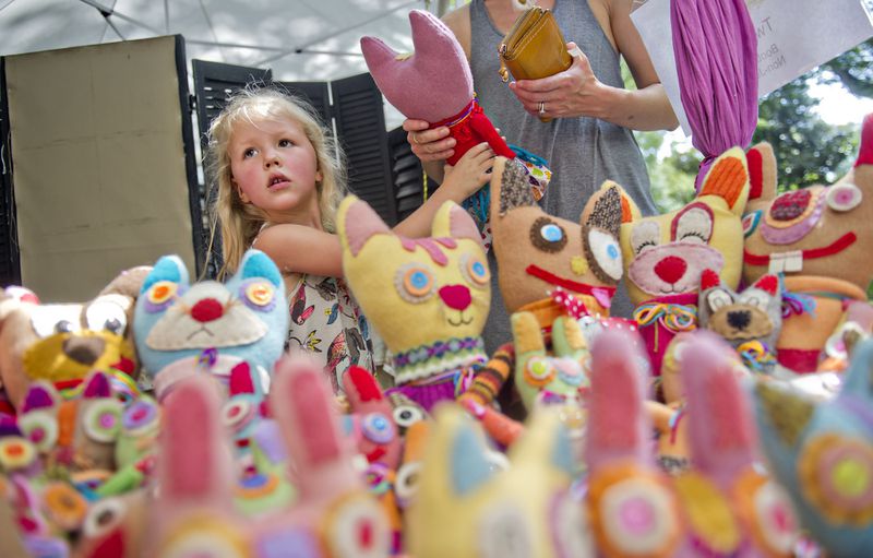 Clementine Boyer (left) hands a stuffed animal to her mother Monika at one of the artist booths during the Grant Park Summer Shade Festival in Atlanta on Saturday, August 23, 2014. Thousands of people came out to check out arts, crafts, food and music during the 12th annual festival. JONATHAN PHILLIPS / SPECIAL