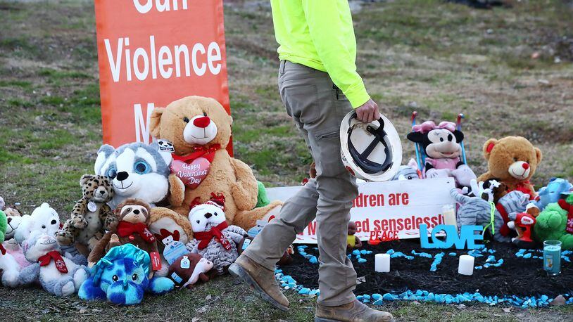 Former firefighter Gage Scarborough, who declined to have his face photographed, visits the growing memorial for 6-month-old Grayson Fleming-Gray outside the Food Mart where the child was shot and killed Jan. 24. (Curtis Compton / Curtis.Compton@ajc.com)