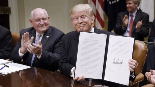 President Donald Trump signs the Executive Order Promoting Agriculture and Rural Prosperity in America as Agriculture Secretary Sonny Perdue looks on during a meeting with farmers on April 25, 2017, in the Roosevelt Room of the White House in Washington, D.C. Perdue was one of only a few Cabinet members to serve in their roles through the Trump administration. (Olivier Douliery/Abaca Press/TNS)