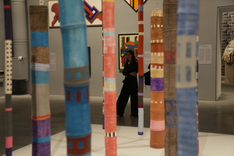A visitor walks next to the 'Bambus' installation by artist Ione Saldanha at the 60th Biennale of Arts exhibition in Venice, Italy, Tuesday, April 16, 2024. The Venice Biennale contemporary art exhibition opens Saturday for its six-month run through Nov. 26. The main show titled 'Stranieri Ovunque – Foreigners Everywhere' is curated for the first time by a Latin American, Brazilian Adrian Pedrosa. Pedrosa is putting a focus on underrepresented artists from the global south, along with gay and Indigenous artists. Alongside the main exhibition, 88 national pavilions fan out from the traditional venue in Venice's Giardini, to the Arsenale and other locations scattered throughout the lagoon city. (AP Photo/Luca Bruno)