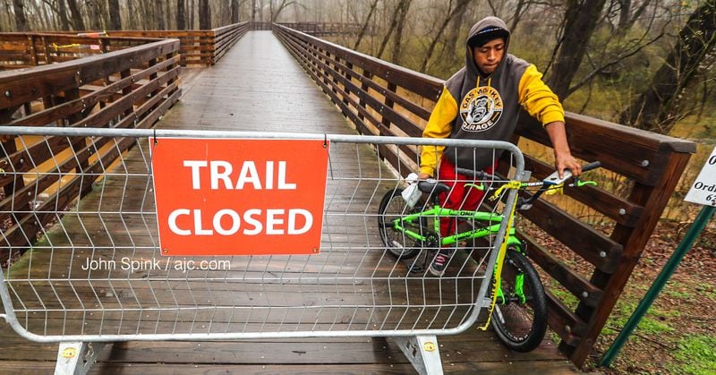 Edwin Lester backs out of riding on the Noonday Creek Bridge in Woodstock on Thursday after officials closed the trail due to flooding. JOHN SPINK / JSPINK@AJC.COM