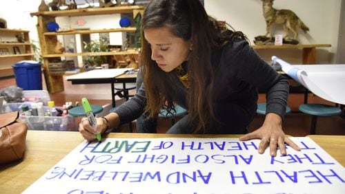 Marinangeles Gutierrez, who plans to participate in Saturday’s Women’s March on Washington, writes her message during a sign-making session Thursday at the Georgia Sierra Club. HYOSUB SHIN / HSHIN@AJC.COM