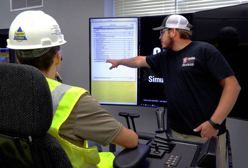 Jimmy Napier, right, a teacher at Jordan Vocational High School, shows Kevin Hunt, 17, a junior at the school, the score he received while working on one of the CAT Simulators in the school’s Heavy Equipment Operator Training Program. (Photo Courtesy of Mike Haskey mhaskey@ledger-enquirer.com)