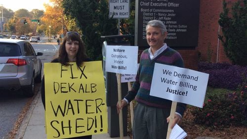 Ellen Buettner and Bill Cox protest DeKalb County’s problem with high water bills outside the Maloof Auditorium on Tuesday. MARK NIESSE / MARK.NIESSE@AJC.COM