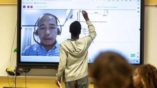 A student writes on a classroom smart board during an 11th grade physics class taught virtually by Bienvenido Oliver at Rockdale Career Academy in Conyers on Friday, Sept. 22, 2023. Elevate K-12 is among the new companies that are helping schools cope with a teacher shortage. (Arvin Temkar / arvin.temkar@ajc.com)