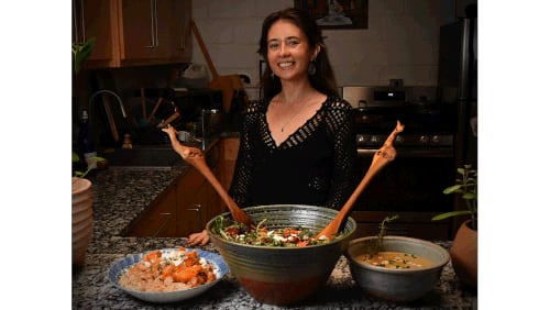 Tatiana Gonzalez is shown in her home kitchen with three winter dishes made from her recipes: (from left) White Bean Chili with Sweet Potatoes, Butternut Squash, Beet, Couscous and Arugula Salad, and Potato Leek Soup. (Styling by Tatiana Gonzalez / Chris Hunt for the AJC)