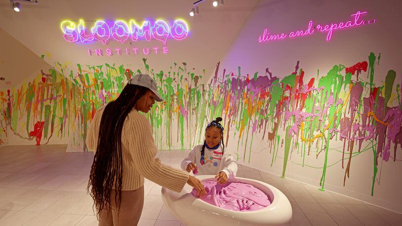 Londyn White, 6, center, and her mother Lawayne Dacosta, of Atlanta, play with the slime at Sloomoo Institute in Buckhead. Jason Getz / Jason.Getz@ajc.com)