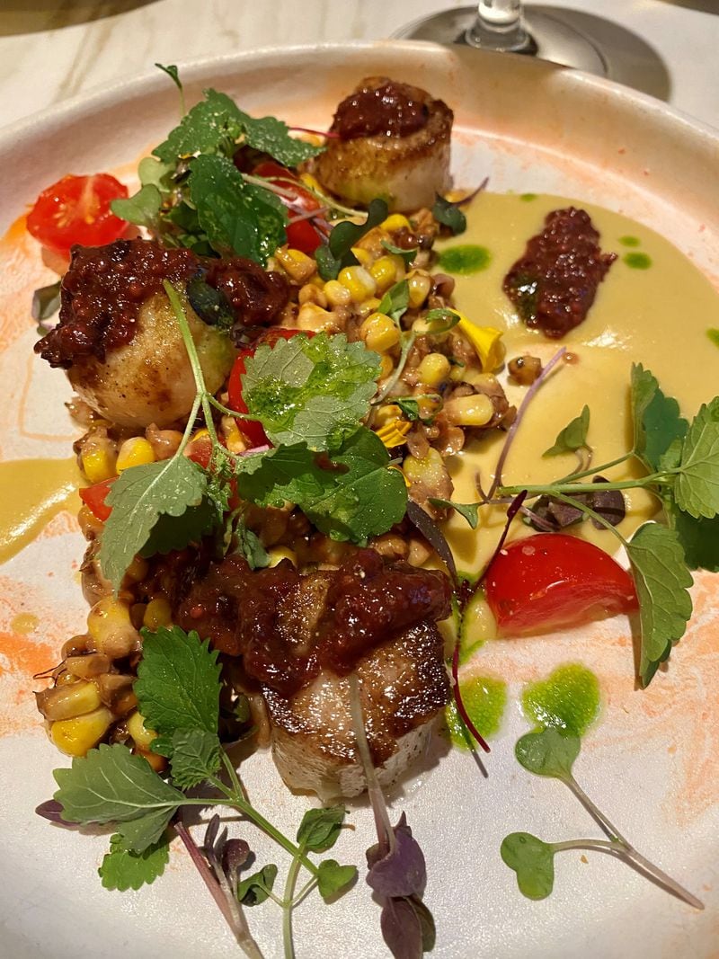 Falling Rabbit’s pan-seared scallops are dressed up with elotes, pickled cherry tomatoes, tart cherry conserva and corn puree. (Wendell Brock for The Atlanta Journal-Constitution)