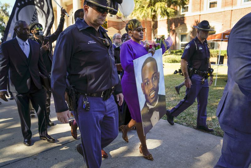 Wanda Cooper-Jones, the mother of Ahmaud Arbery, carries a portrait of her son after exiting the Glynn County Courthouse in Brunswick, Ga., Nov. 23, 2021. The judge has concluded his instructions, and jurors will now begin deciding the fate of the three men accused of murdering Arbery. (Nicole Craine/The New York Times)