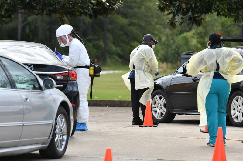 Medical workers in protective gear collect samples at a Phoebe Putney Health System drive-through testing site in Albany on Tuesday. As of Thursday, more than 1,400 people tested through the health system were still awaiting their results. HYOSUB SHIN / HYOSUB.SHIN@AJC.COM
