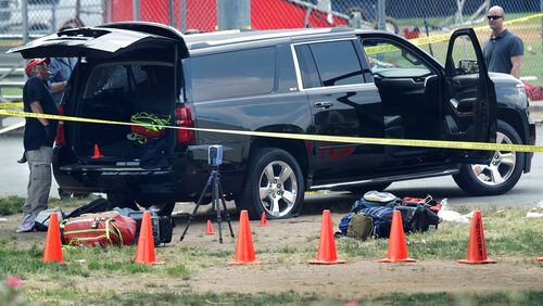 Investigators survey a black SUV with a flat tire and a hole on its windshield outside the Eugene Simpson Stadium Park, where U.S. House Majority Whip Rep. Steve Scalise, R-La., and multiple congressional aides were shot by a gunman during a Republican baseball practice. Alex Wong/Getty Images