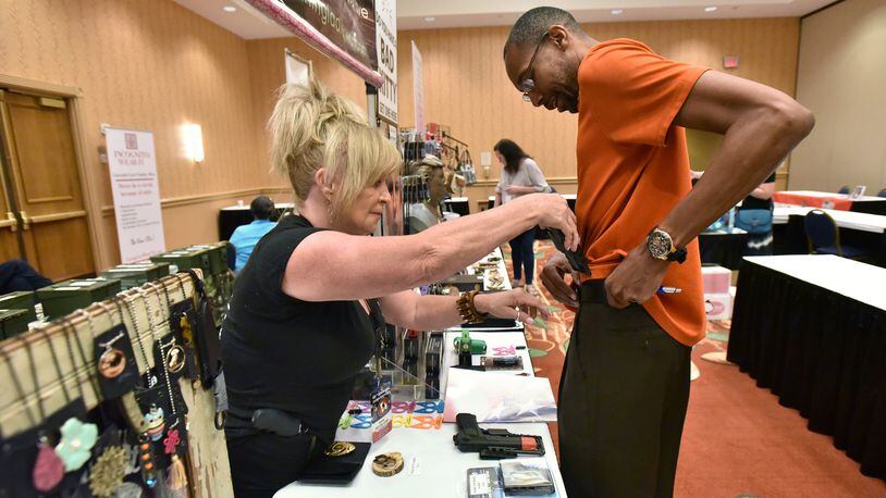 Tammy Jensen with Stunning Ladies helps Carl Bennett of Marietta with gun accessories during a Georgia Carry convention. An Atlanta Journal-Constitution poll found that about 70% of registered voters oppose the idea of allowing people to carry handguns without a permit. HYOSUB SHIN / HSHIN@AJC.COM
