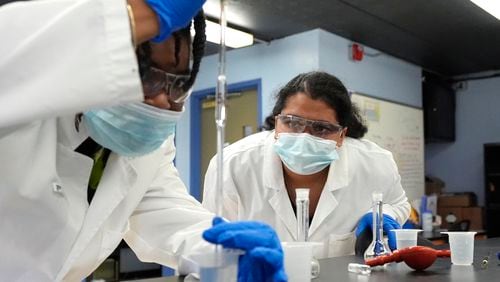 Sima Gutierrez, right, observes as a teammate examines water at the Flint Community Water Lab, Wednesday, April 3, 2024, in Flint, Mich. The lab, with more than 60 high school and college interns, has provided free water testing for thousands of residents since 2020. (AP Photo/Carlos Osorio)