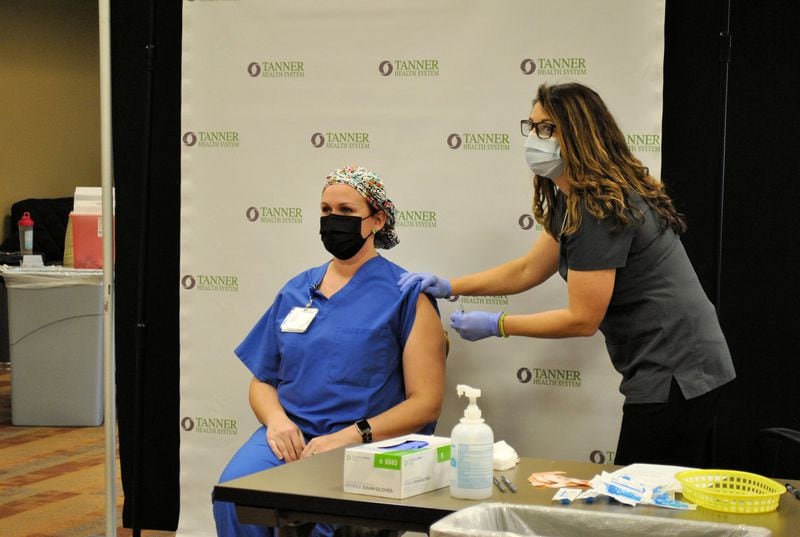 Kaite Scogin, a registered nurse at Tanner Health System, a hospital system in west Georgia stretched thin by the pandemic, receives the COVID-19 vaccine.  There are not enough doses yet to vaccinate all hospital staff, much less the patient population, and the pandemic is expected to continue for months.  