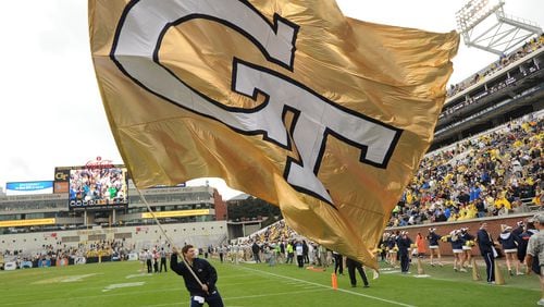 A Georgia Tech cheerleader waves the giant GT flag after a Georgia Tech touchdown in Bobby Dodd Stadium on Saturday, October 19, 2013. JOHNNY CRAWFORD / JCRAWFORD@AJC.COM