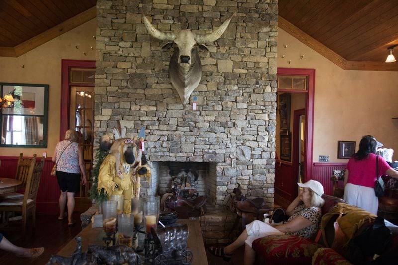 People sit among items ready to be auctioned off at Tex and Diane McIver's ranch in Eatonton, Ga., on Saturday, Aug. 4, 2018. (Photo: STEVE SCHAEFER / SPECIAL TO THE AJC)
