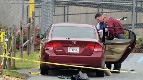 April 29, 2014 Kennesaw, GA: Police officials examine a car located at the scene of the shooting that took place at a FedEx facility in Kennesaw, GA. BRANT SANDERLIN /BSANDERLIN@AJC.COM .
