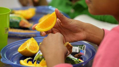 Samayah Jones enjoys an orange during afternoon snack time recently at East Atlanta Kids Club. The club is one of 20 child care programs and camps that will provide free meals to needy children this summer when many often go without. BRANT SANDERLIN / BSANDERLIN@AJC.COM