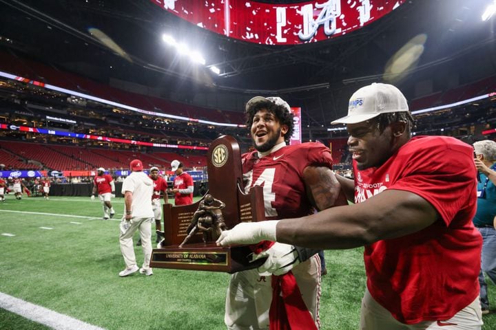 Alabama Crimson Tide players including offensive lineman Kadyn Proctor (74) celebrate after defeating the Georgia Bulldogs 27-24 in the SEC Championship football game at the Mercedes-Benz Stadium in Atlanta, on Saturday, December 2, 2023. (Jason Getz / Jason.Getz@ajc.com)