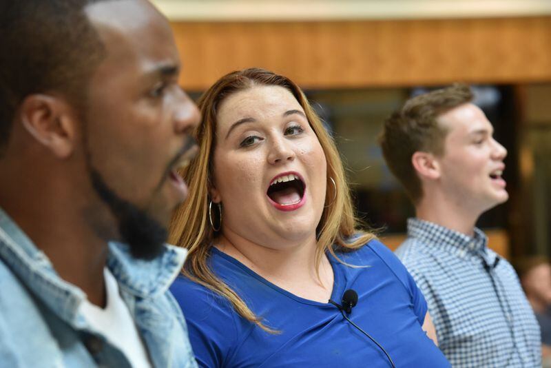   Lead vocalist Ali Ramsaier (center) performs in a flash mob at Hartsfield-Jackson International Airport's domestic terminal atrium on Friday, Aug. 3, 2018. Lindsey Eastwood organized the gathering to welcome her husband, Jon Eastwood, from the United Kingdom. They were married July 27, 2017, at his church in North Wales, and the last time Lindsey saw Jon was May 6, 2018. This is the longest they have gone without seeing each other since they were engaged because they were not sure about the immigration approval timing. They applied for his visa to come to the U.S. immediately after their marriage, and Jon's visa was only just granted by the U.S. in mid-July 2018.  (Photo: HYOSUB SHIN / HSHIN@AJC.COM)