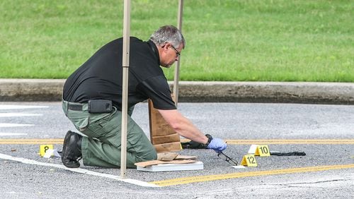 A Douglas County investigator places evidence markers at an active shooting investigation Wednesday morning Photo: JOHN SPINK / JSPINK@AJC.COM