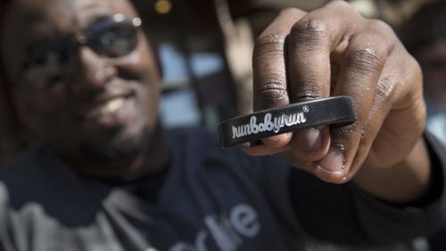 Sean Roberson holds one of his custom bracelets with his company’s name on it, before starting his run on May 22, 2015, through Piedmont Park in Atlanta. After Roberson donated one of his kidneys to his older brother, he started a running apparel line to help others live a healthier life. STEVE SCHAEFER / SPECIAL TO THE AJC
