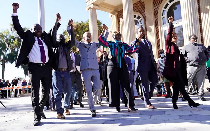 The Rev. Al Sharpton, third from the left, holds hands with Ahmaud Arbery‚Äôs parents, Wanda Cooper-Jones, right, and Marcus Arbery, left, as they react outside the Glynn County Courthouse in Brunswick, Ga., on Wednesday, Nov. 24, 2021, after the jury found three men guilty of murder and other charges for the pursuit and fatal shooting of Ahmaud Arbery. (Nicole Craine/The New York Times)