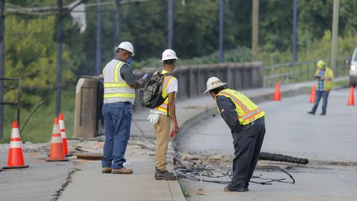 Workers assess the damage on Cheshire Bridge Road after a fire early Thursday morning ruptured a gas line and compromised a bridge.