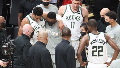 Milwaukee Bucks forward Giannis Antetokounmpo is helped up by his brother Thanasis (right), who also plays for the team, after he hyperextended his left knee. (Curtis Compton / Curtis.Compton@ajc.com)