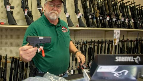 Salesman Hugh Jeffries hands a Taurus handgun to a customer at Adventure Outdoors in Smyrna, Monday, December 13, 2021. STEVE SCHAEFER FOR THE ATLANTA JOURNAL-CONSTITUTION