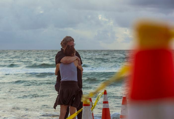 Onlookers embrace on the beach near the partially collapsed 12-story Champlain Towers South condo building in Surfside, Fla., Friday morning June 25, 2021. (Saul Martinez/The New York Times)