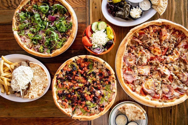 The Greek Pizzeria and Gyros Vegan Pizza, Supreme Vegetarian Specialty Pie, Meat Lovers Specialty Pie, Gyro Platter, Sampler Platter, and sides of pita and a Greek salad. (Mia Yakel for The Atlanta Journal-Constitution)