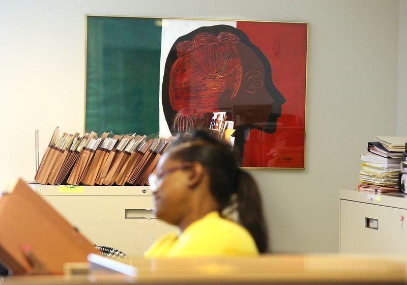 An office worker sorts file folders next to an untitled female profile by artist Freddie Styles at the Atlanta Life Financial Group. Says a board member: “We are an insurance firm. We can’t have people walking around our offices looking at art.” Curtis Compton / ccompton@ajc.com