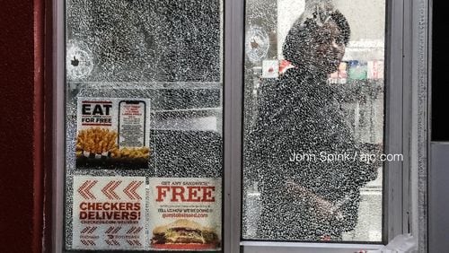 Bullet holes can be seen in the walk-up window of a Checkers restaurant on Candler Road after a shooting early Wednesday.