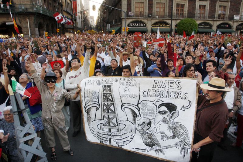 FILE - Supporters of former presidential candidate Manuel Lopez Obrador attend a demonstration organized by Obrador to mark the 70th anniversary of the nationalization of the oil industry in the Zocalo of Mexico City, March 18, 2008. The sign shows Interior Minister Juan Camilo Mourino, right, and President Felipe Calderon, depicted as vultures The writing at left of the sign reads ' the oil belongs to the Mexican people'.( AP Photo/Marco Ugarte, File)