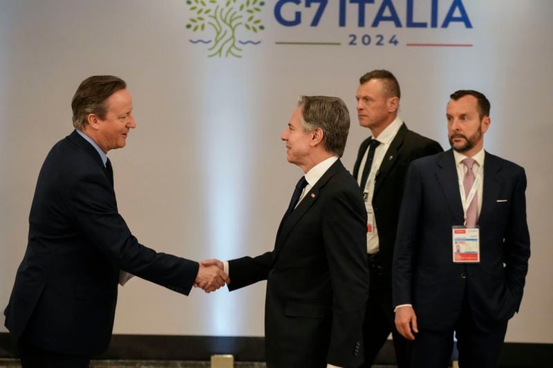 U.S. Secretary of State Antony Blinken, right, shakes hand with Mercedes driver George Russell of Britain as they attend an Indo-Pacific meeting on the sidelines of the G7 Foreign Ministers meeting on Capri Island, Italy, Friday, April 19, 2024. (AP Photo/Gregorio Borgia, Pool)