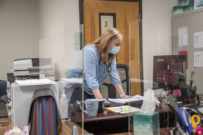 In this file photo, Mill Creek High School nurse Kathy Catapano reads through emails at her desk in the school’s clinic in Hoschton. (Alyssa Pointer / Alyssa.Pointer@ajc.com)