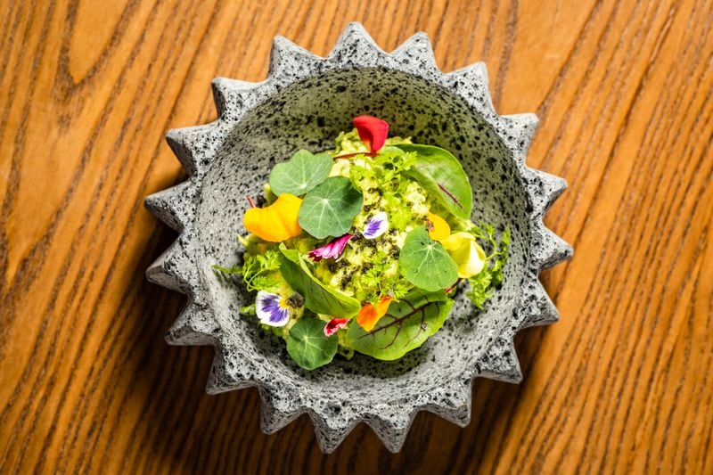 Palo Santo's guacamole is garnished with edible flowers and comes with a house-made blue corn tortilla intended to be broken into smaller pieces by diners. Courtesy of the Cocktail Shaker
