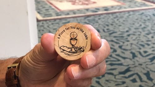 Mike Malone from Greensboro, Ga. holds a wooden token give to delegates at the 2022 meeting of the North Georgia Conference  of the UMC in Athens.