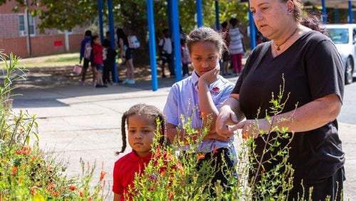 Teacher Nathan Strange (right) shows kindergartener Andrea Welmaker and sixth-grader Alaina Welmaker around one of the gardens at The Main Street Academy in College Park. CONTRIBUTED BY PHIL SKINNER
